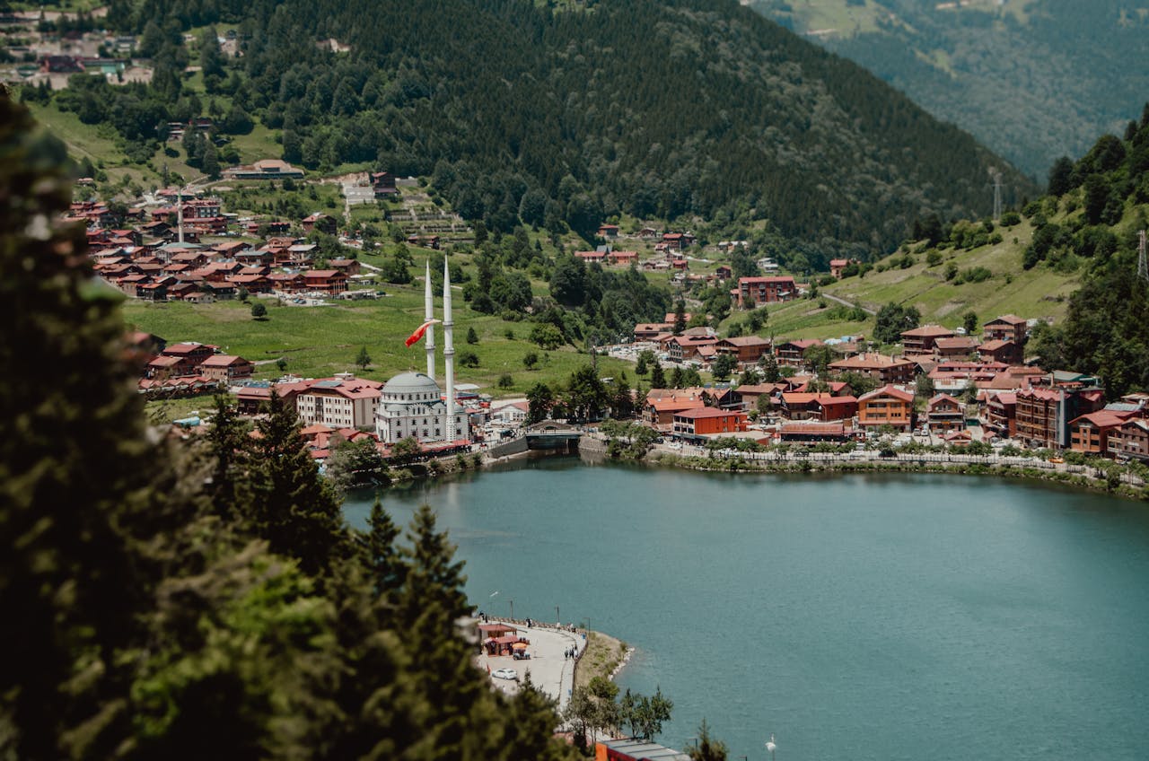 A scenic view of Uzungöl village in Türkiye, surrounded by lush green mountains and a tranquil lake.